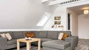 A modern living room with a grey sectional sofa, a wooden coffee table, and a skylight above. - 8 Person Holiday Home in Harboore (Harboore)