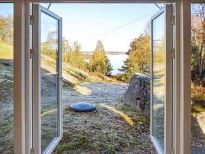 A view through a glass door with a landscape of a lake, trees, and a path. - 5 Person Holiday Home in Klovedal (Klovedal)