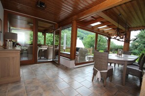 A covered patio with a dining area, wicker furniture, and a view of the surrounding greenery. - Apartment Haus am Berg, Lonau (Herzberg am Harz)