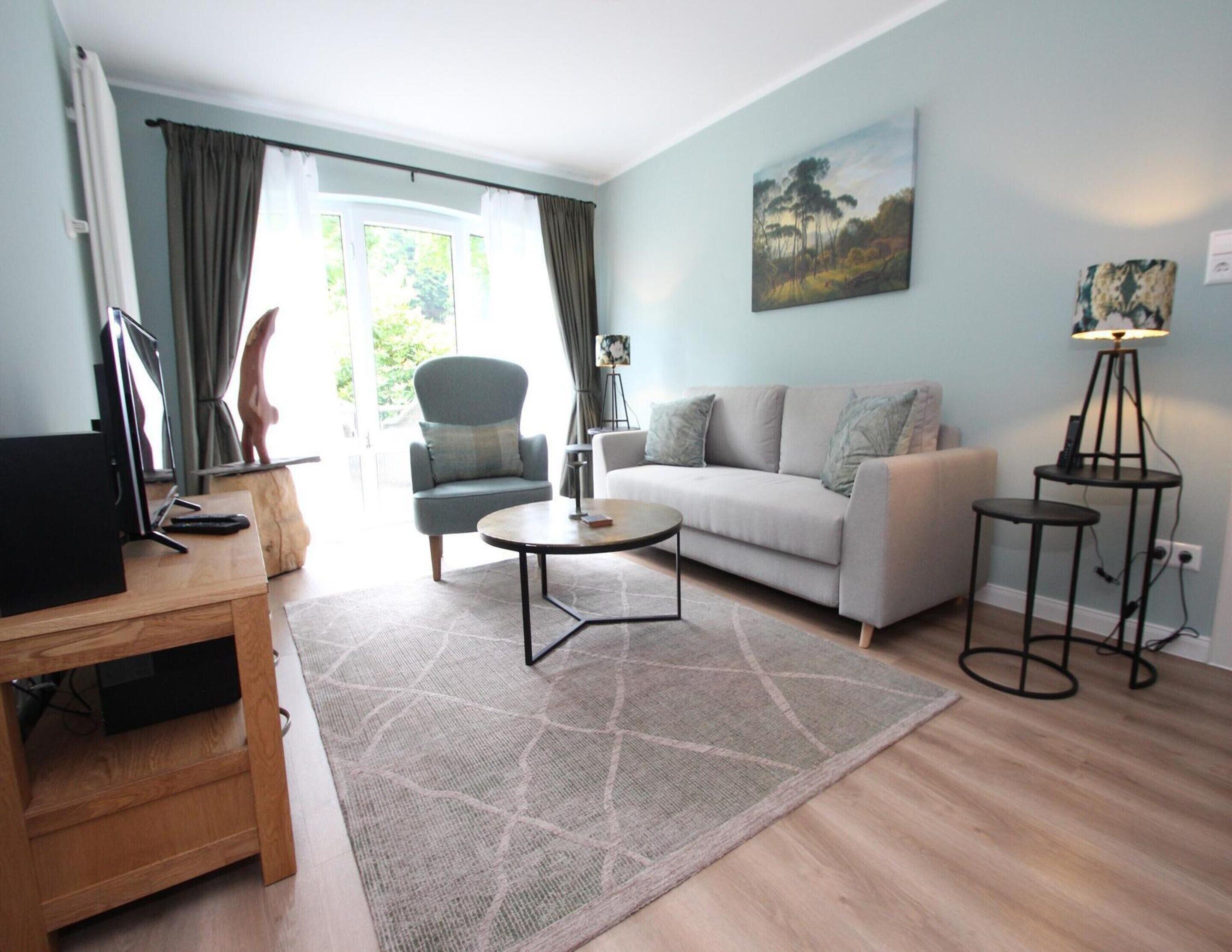 Un salon moderne avec un canapé, une table basse et un téléviseur posé sur un meuble en bois.