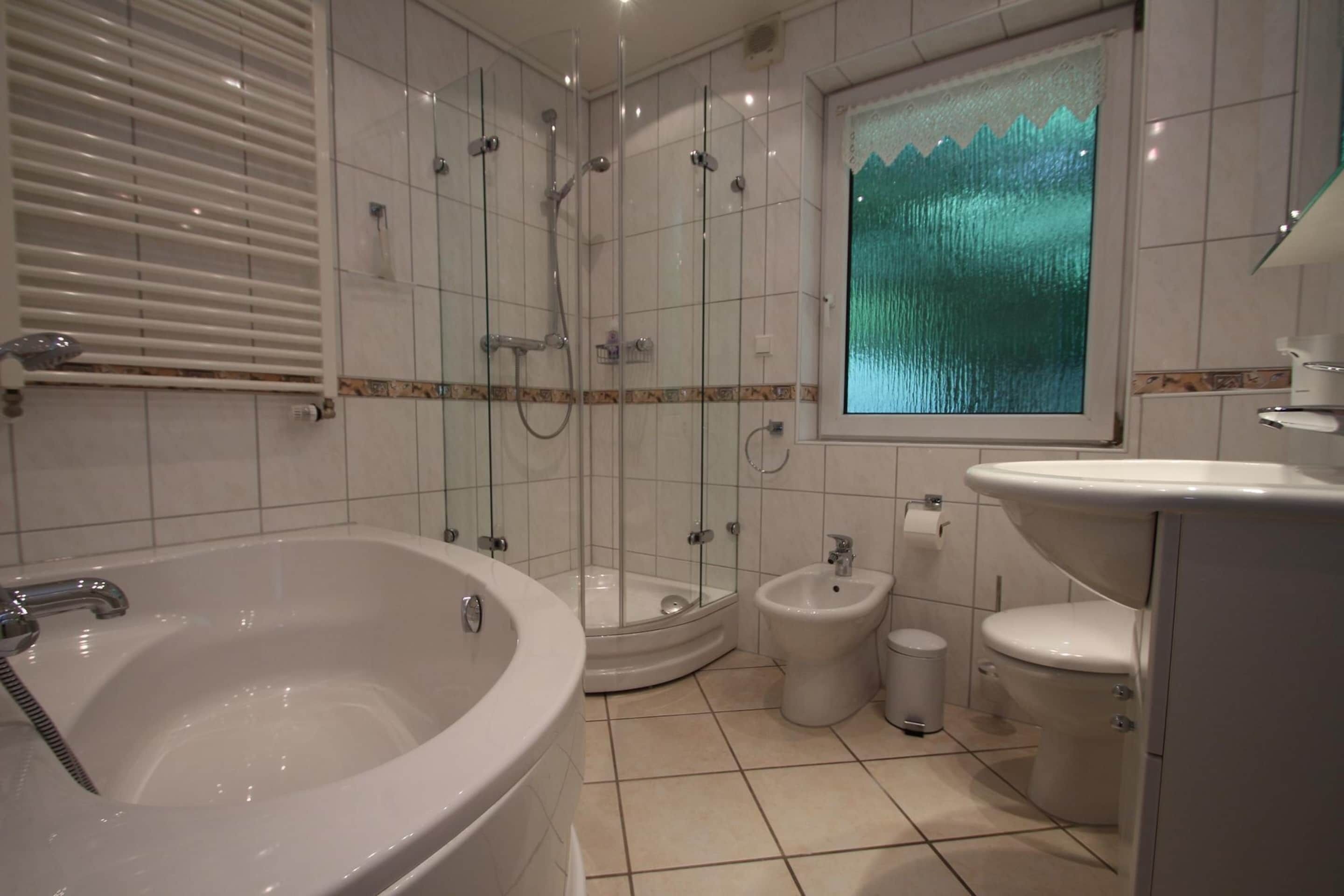 A bathroom with a bathtub, a shower enclosure, a bidet, and a toilet.