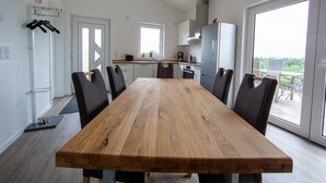 Een moderne keuken met witte kastjes, een roestvrijstalen koelkast en een eethoek met een houten tafel en stoelen.