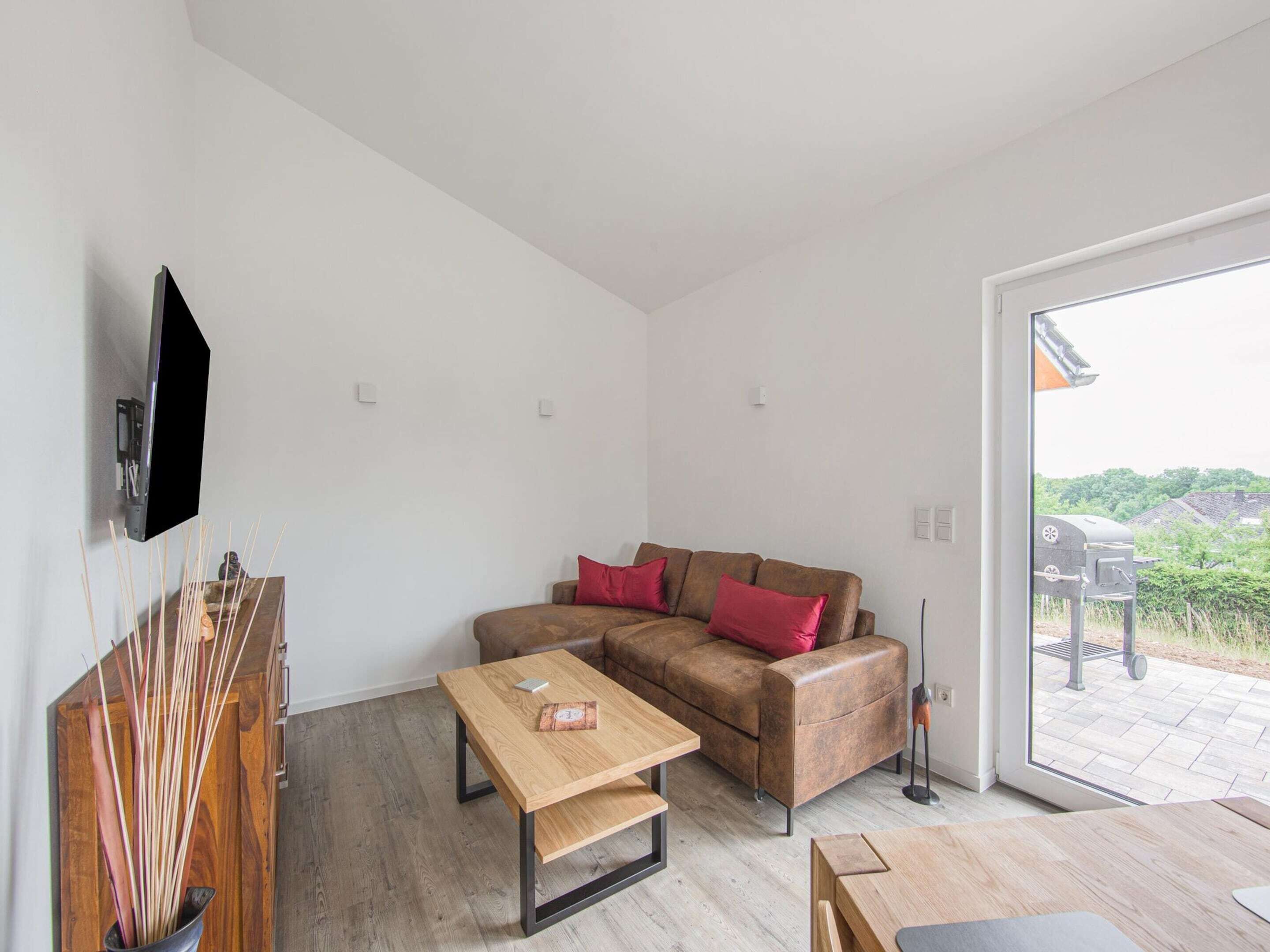 A modern living room with a sofa, a coffee table, and a TV mounted on the wall.