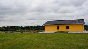 A yellow building with a tiled roof in a grassy field.