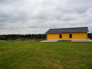 Keltainen rakennus, jonka katto on päällystetty tiilillä, sijaitsee ruohikkoisella niityllä.