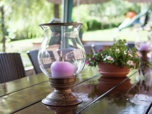 A candle in a glass holder on a wooden table. - Atmospheric Holiday Home in Durbuy With Sauna (Durbuy)