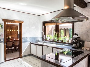 A modern kitchen with a central island, built-in oven, and a large window overlooking greenery. - Atmospheric Holiday Home in Durbuy With Sauna (Durbuy)