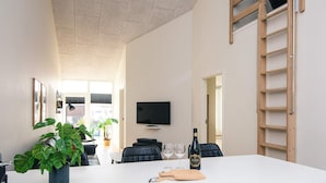 A modern kitchen with a central island, a TV mounted on the wall, and a wooden ladder. - 8 Person Holiday Home in Ringkobing (Ringkobing)