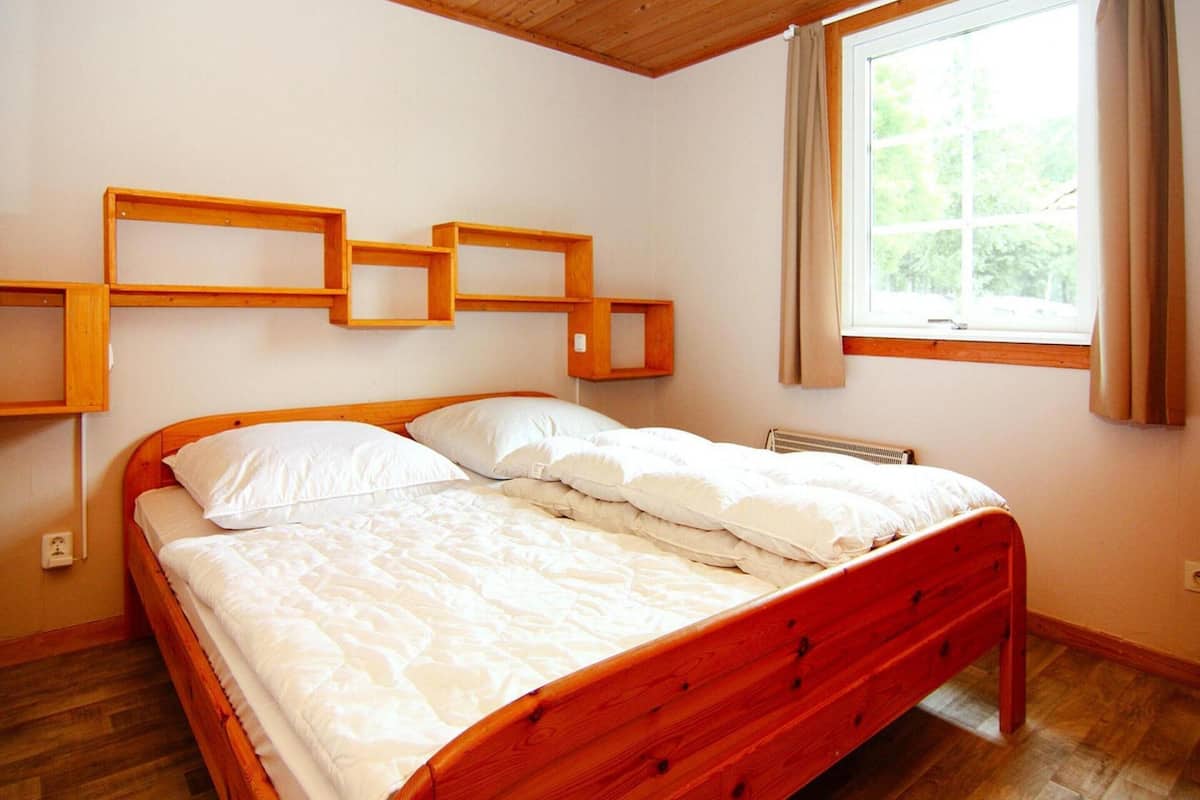 Una cama de madera en una habitación con ventana y estanterías empotradas.