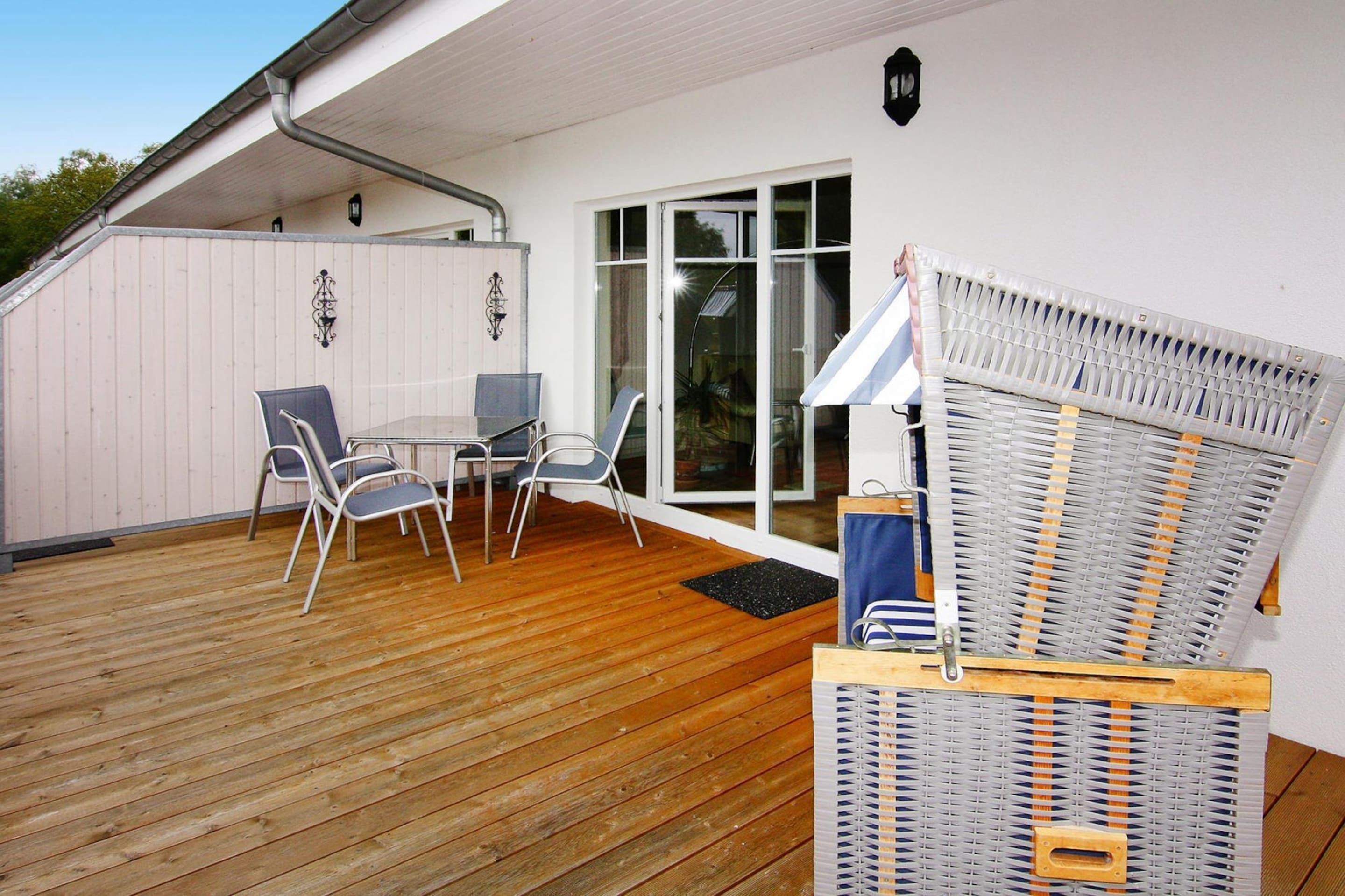 A wooden deck with outdoor furniture, a covered seating area, and a large window.
