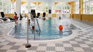 Una piscina al coperto con pavimento a scacchi, diverse corsie e una postazione per il bagnino.