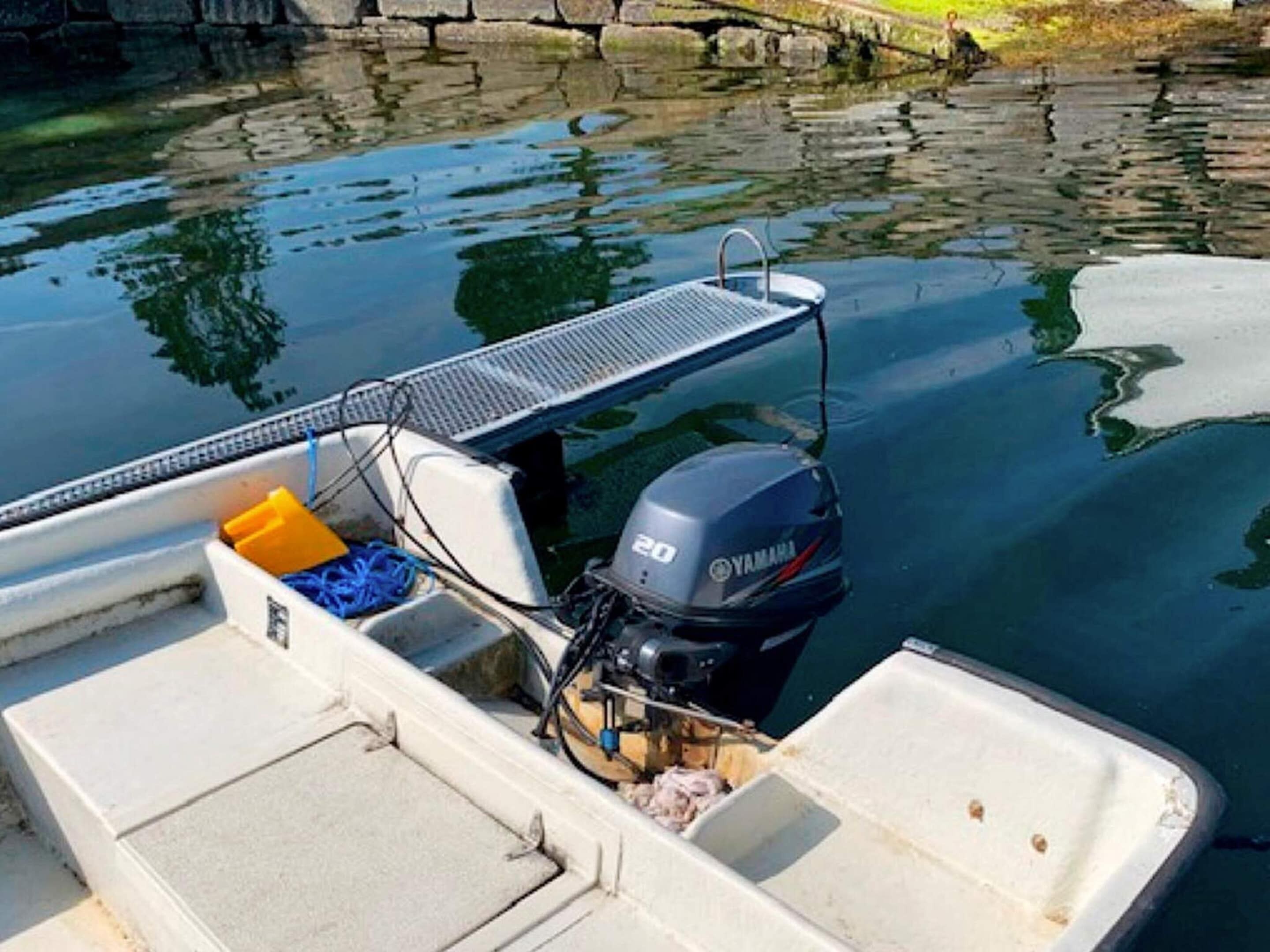A small boat with a Yamaha outboard motor, a metal platform, and a white interior.
