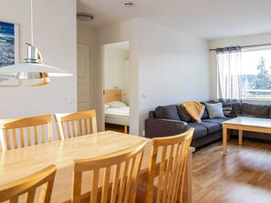 Enjoy a comfortable stay in this stylish living space with a dining area, sofa, and large window offering a view of the outdoors.
