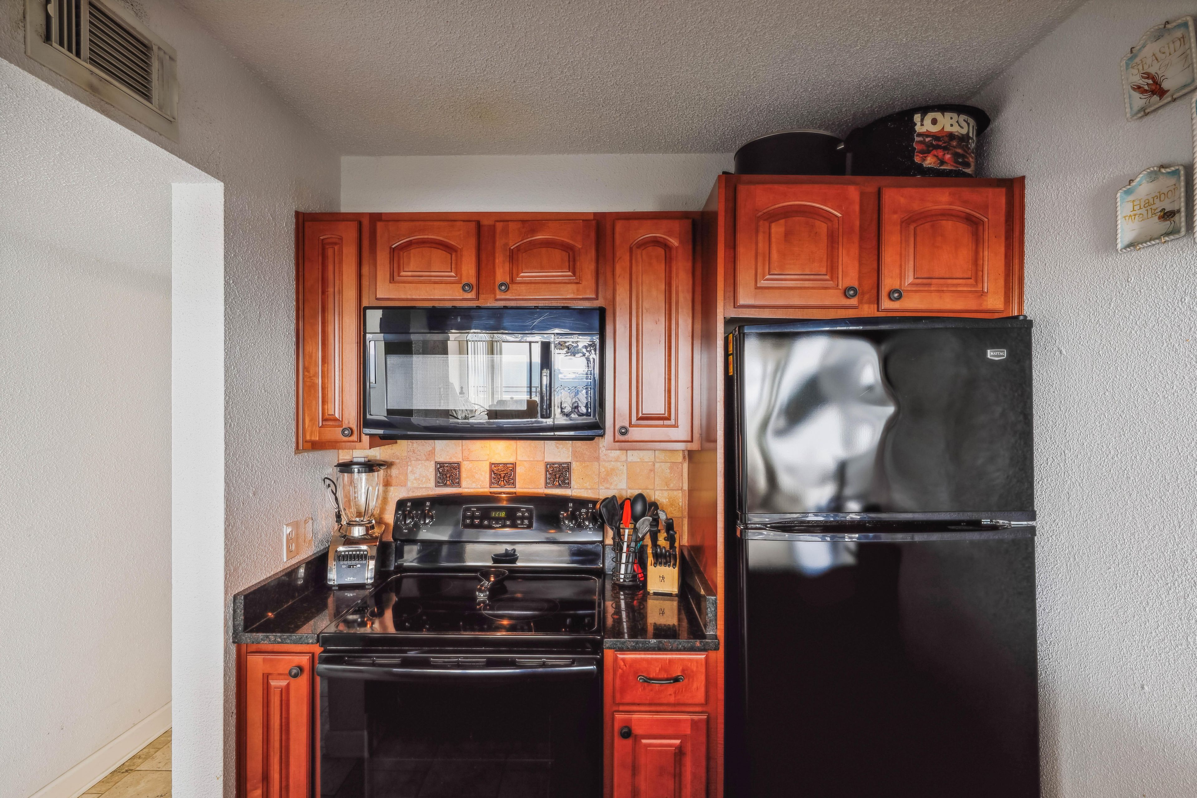 A kitchen with wooden cabinets, a black refrigerator, a stove, and a microwave.