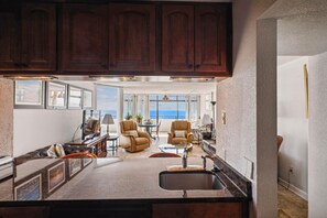 A kitchen with a large island, wooden cabinets, and a view of the ocean. - Includes Xplorie Activities and Linens. PYRAMID - 1BR oceanfront condo w/outdoor pool. (Ocean City)