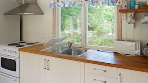 A kitchen with a stove, sink, and window with a view of greenery. - 4 Person Holiday Home in Smedstorp (Smedstorp)