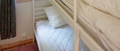 A bunk bed with white bedding, a window with a view of greenery, and a red carpeted floor.