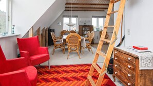A loft-style room with a dining area, red chairs, a wooden ladder, and a herringbone-patterned rug. - 6 Person Holiday Home in Ribe (Ribe)