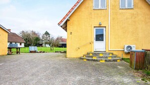 A yellow building with a white door and a small porch. - 6 Person Holiday Home in Ribe (Ribe)