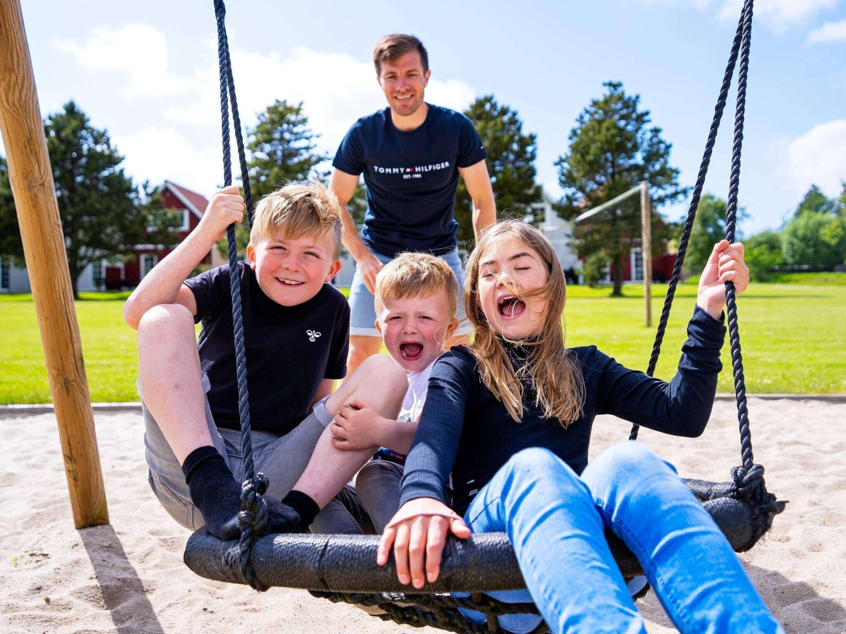 En gunga i en park, bestående av en trästolpe, en gungbräda och ett rep.