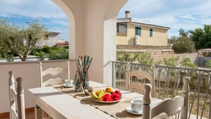 Een balkon met een tafel gedekt voor twee personen, inclusief een fruitschaal en een kopje.