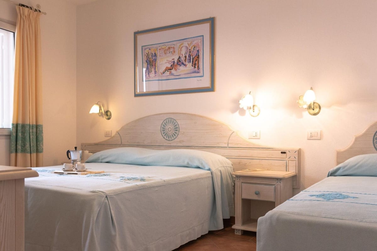 Une chambre d’hôtel avec deux lits, un tableau au mur et des lampes de chevet.