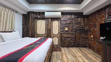 Een slaapkamer met een bed, houten wandbekleding, een airconditioning en een televisie op een glazen tafel.