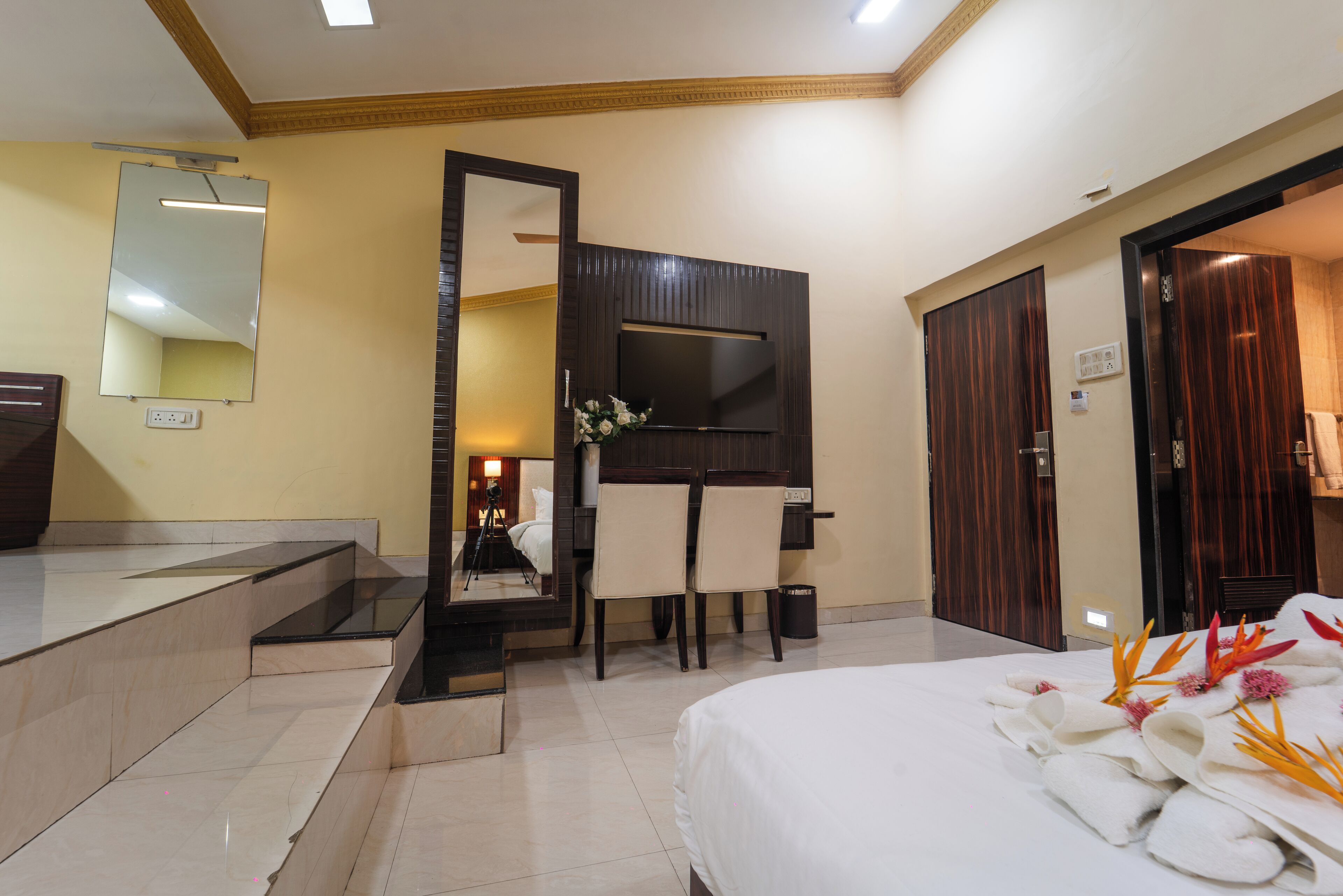 A hotel room with a bed, a desk with a chair, a TV, and a mirror.