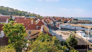 A coastal town with traditional architecture, a marina, and a view of the sea. - 4 Person Holiday Home in Gudhjem (Gudhjem)