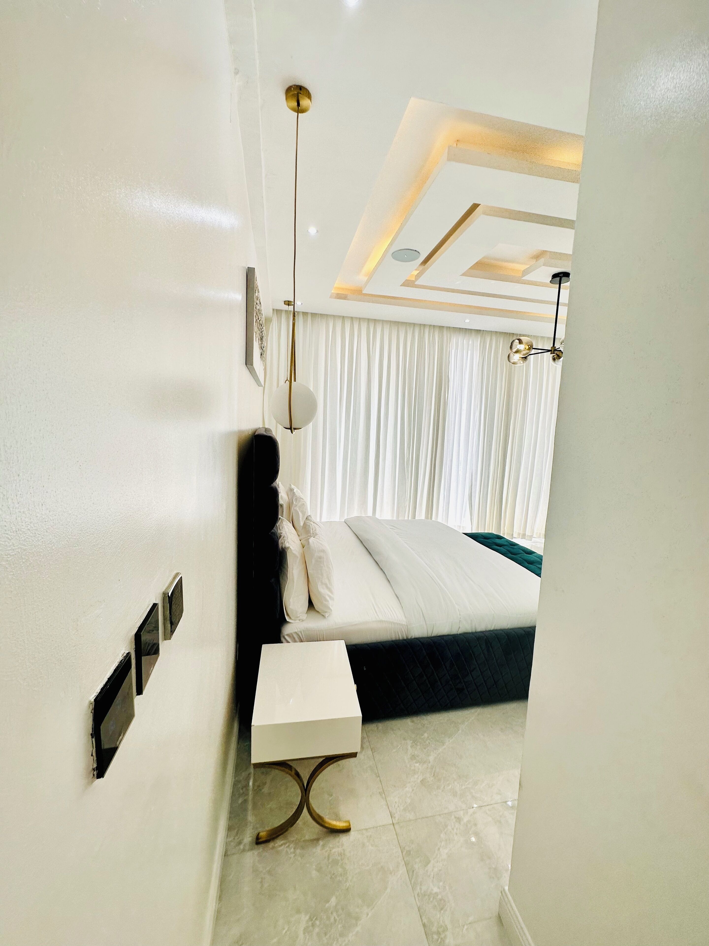 Un dormitorio moderno con cama, mesita de noche y lámpara del techo.
