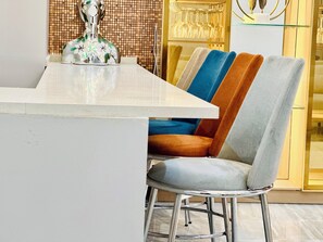 A modern dining area with a white marble table, a decorative vase, and a glass cabinet with wine glasses. - Lekki Villas (Lekki)