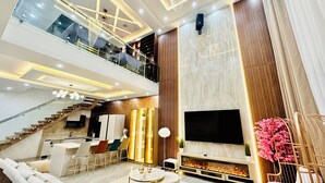 A spacious living area with a modern design, featuring a large flat-screen TV, comfortable seating, a fireplace, and a balcony with glass railings. - Lekki Villas (Lekki)