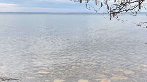 A calm lake with clear water, surrounded by rocks and driftwood. - 4 Person Holiday Home in Granna (Gränna)
