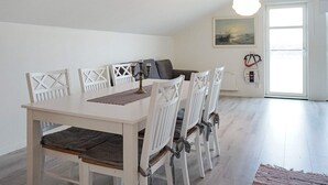 A dining area with a white table and chairs, a gray sofa, and a painting on the wall. - 6 Person Holiday Home in Kungshamn (Kungshamn)