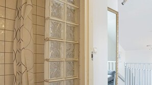 A room with a tiled wall, a glass door with a grid pattern, a white door frame, and a mirror with a gold frame. - 6 Person Holiday Home in Kungshamn (Kungshamn)