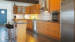 A modern kitchen with wooden cabinets, a stainless steel refrigerator, and a built-in oven. - 6 Person Holiday Home in Kungshamn (Kungshamn)
