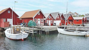 A waterfront with red buildings, docked boats, and a calm water surface. - 6 Person Holiday Home in Kungshamn (Kungshamn)