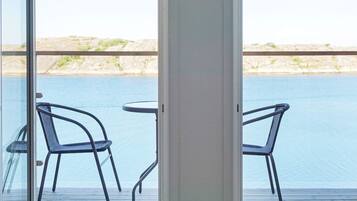A balcony with two chairs and a table overlooking a body of water.