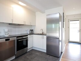 Una cocina moderna con armarios blancos, electrodomésticos de acero inoxidable y un refrigerador grande.