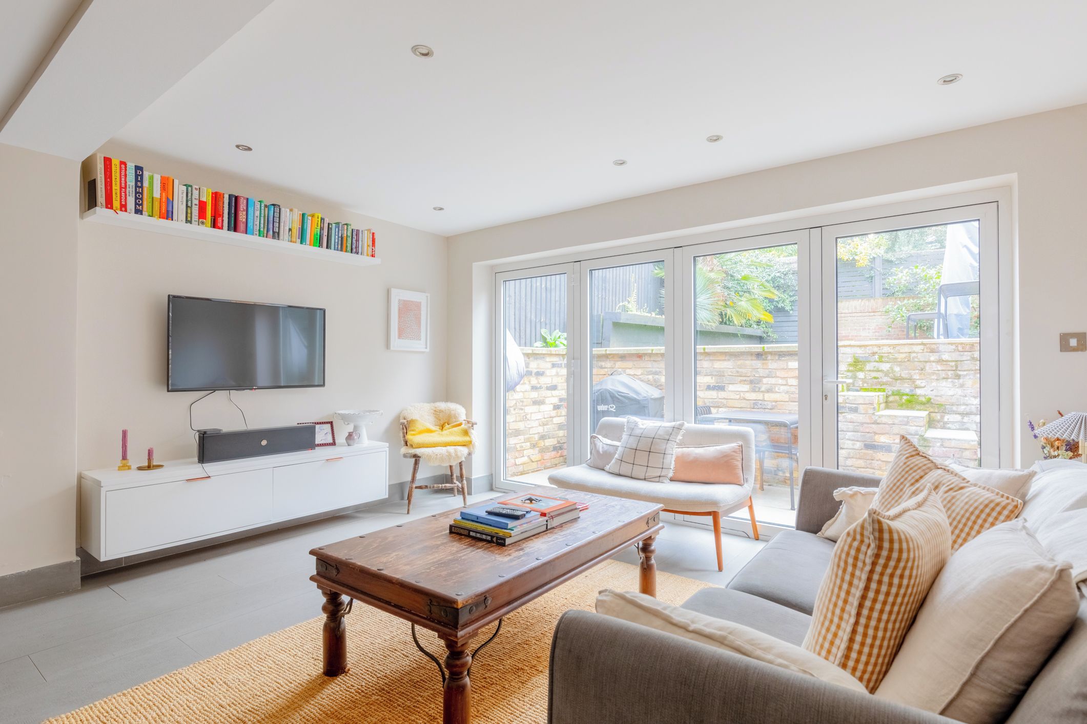 A modern living room with a flat-screen TV, a bookshelf, a coffee table, and a sofa.
