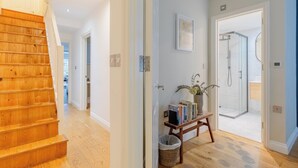 A staircase leading to a hallway with a wooden bench, a basket, and a framed picture. - Contemporary 2BD Cottage-Style Flat, Hackney (Greater London)