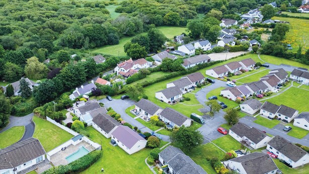 Vista aérea de uma área residencial com casas, ruas e uma orla costeira.