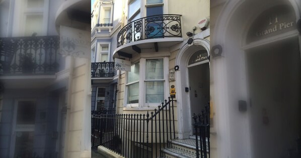 A corner building with a balcony, a door labeled 'Grand Pier,' and a sign with 'AA' on it.