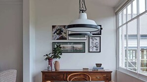 A dining area with a wooden table, chairs, a pendant light, and artwork on the wall. - Sunny, spacious three bedroom apartment with views (Battery Point)