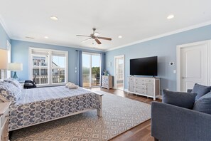 Ein Schlafzimmer mit Bett, Fernseher, Kommode und einem Balkon.