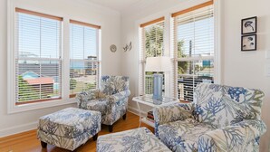 Un salon avec vue sur l’extérieur, comprenant deux fauteuils, une table d’appoint et une lampe.
