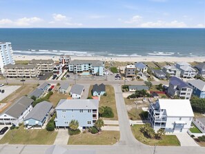 Una zona residencial costera con propiedades frente a la playa, una piscina y una playa al fondo.