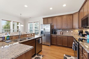 Cocina moderna con encimeras de granito, electrodomésticos de acero inoxidable y armarios de madera.