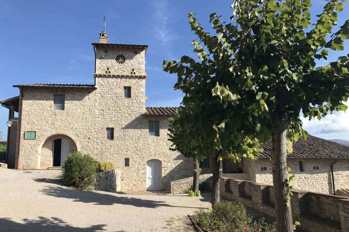Un bâtiment en pierre doté d’une tour, de portes en arc de cercle et d’un petit jardin.