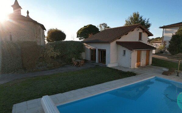 Il s’agit d’une propriété résidentielle dotée d’une piscine, d’un petit jardin et d’un bâtiment en pierre en arrière-plan.